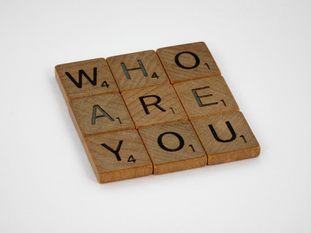 Scrabble tiles spelling "Who Are You," symbolizing the loss of identity in the era of digital afterlives and data immortality.