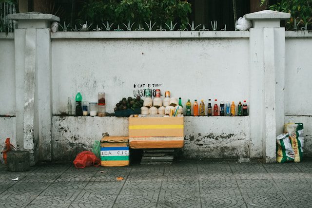 Một quầy hàng rong Việt Nam bán nước dừa, trái cây và nước ngọt bên vỉa hè – hình ảnh gợi nhớ ký ức đô thị trong Từ Mộng.